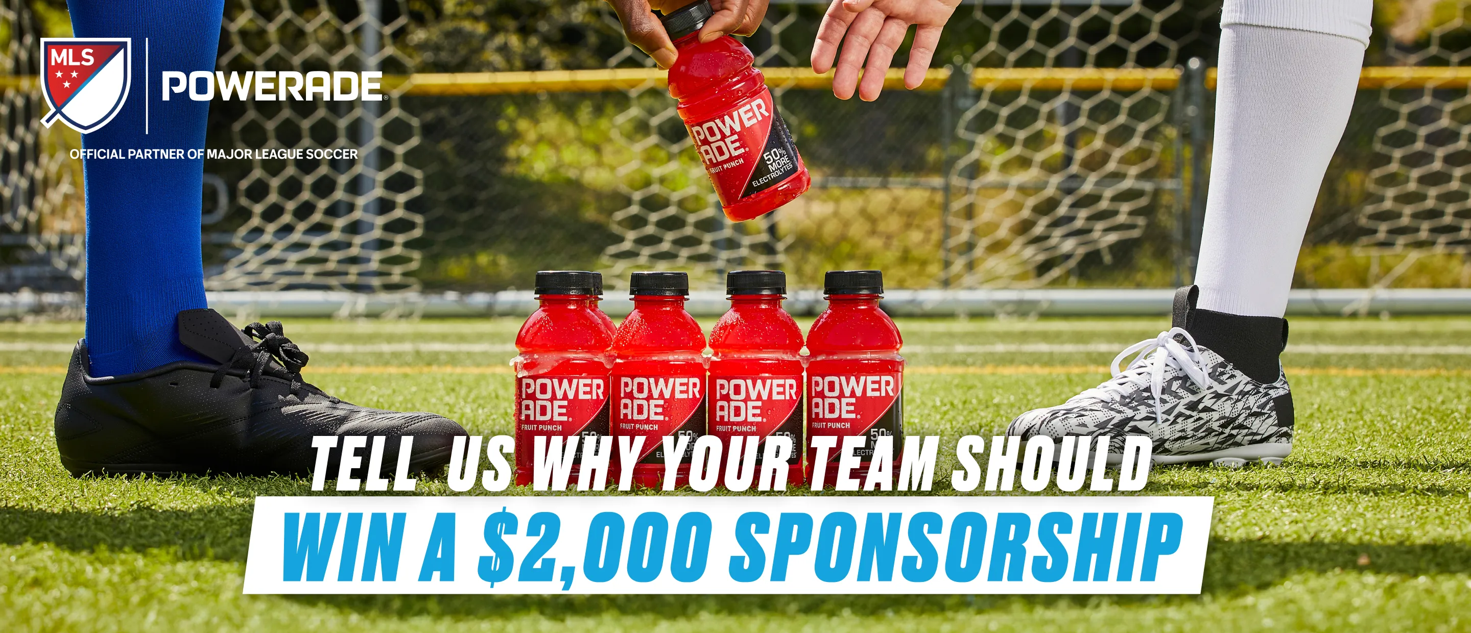 A soccer field scene shows two players' legs in cleats and socks flanking four Powerade Fruit Punch bottles, with a hand pouring another bottle above them. The MLS and Powerade logos appear top left, with text reading "Tell us why your team should win a $2,000 sponsorship